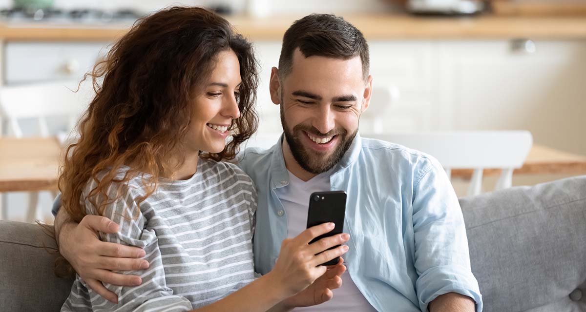 Happy couple looking at their home inspection report on a a smartphone 